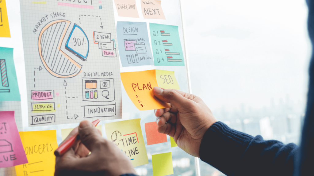 man organising and strategizing using paper, pen and sticky notes