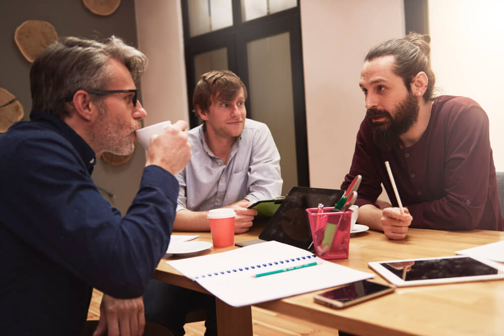 A behind-the-scenes photo of a team in candid conversation or a founder writing notes at their desk.