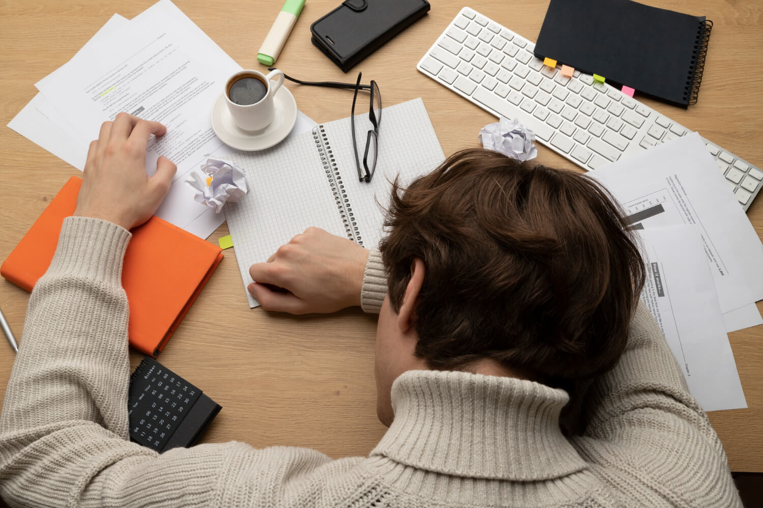 A person at a desk, surrounded by crumpled drafts, clearly over-editing and overthinking.